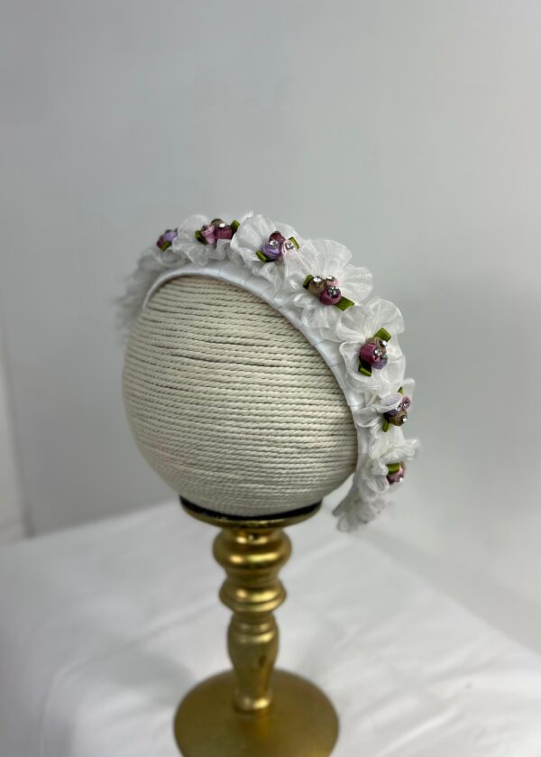 Diadema blanca con flores pequeñas y detalles en tonos lila y rosa